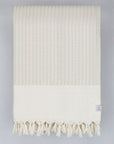 Folded soft cotton blanket with a gentle waves pattern in beige colour.