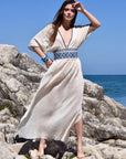 Long cream 100% cotton summer maxi dress with v-neck and blue knitted blue patterns around the waist.