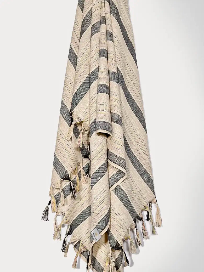 Towel with thin and thick colourful vertical stripes and hand twisted & knotted fringe hanging.