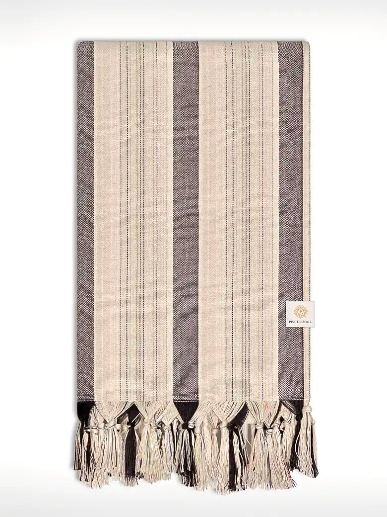 Folded towel with thin and thick colourful vertical stripes and hand-twisted & knotted fringe.