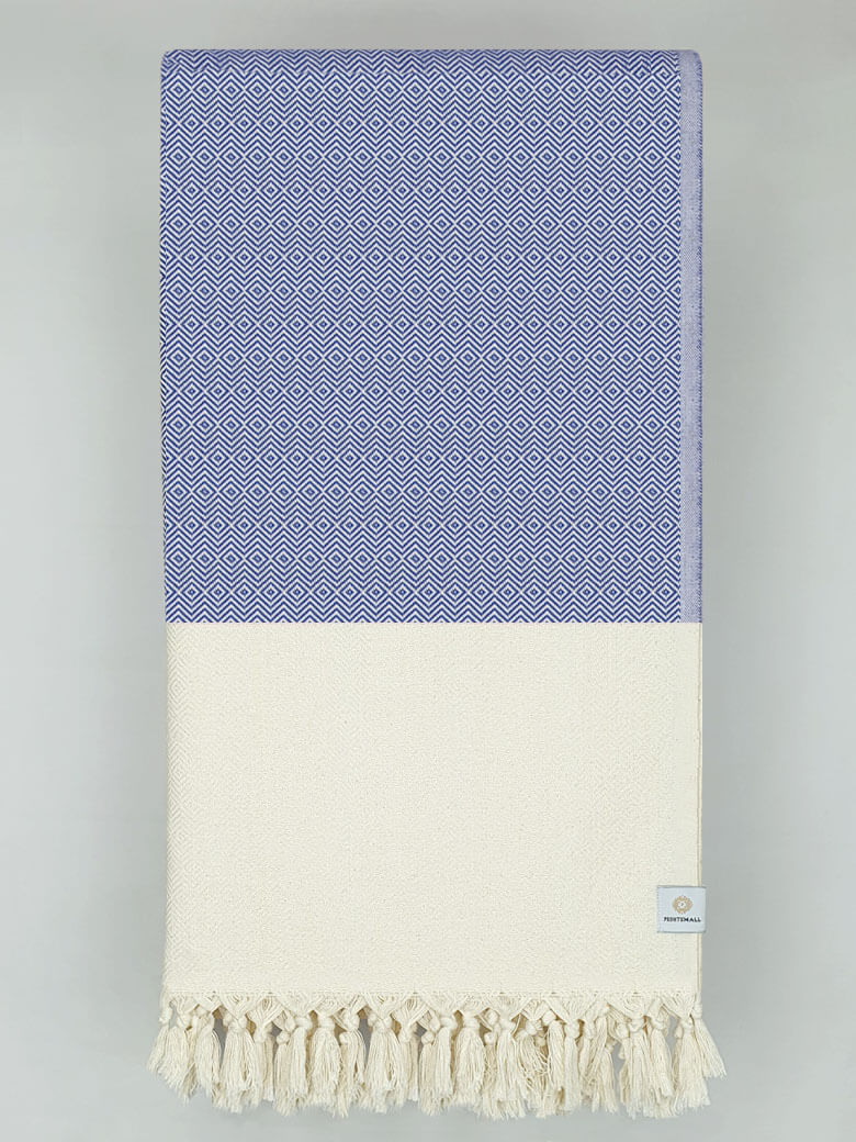 Folded woven cotton blanket with a modern diamond pattern in blue &amp; half part of a beige colour.