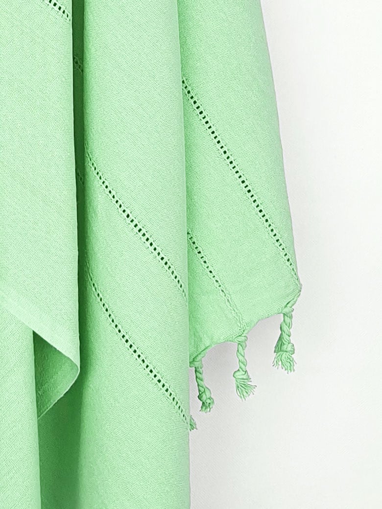 Close-up image of a cotton scarf in plain green colour with knotted fringe.