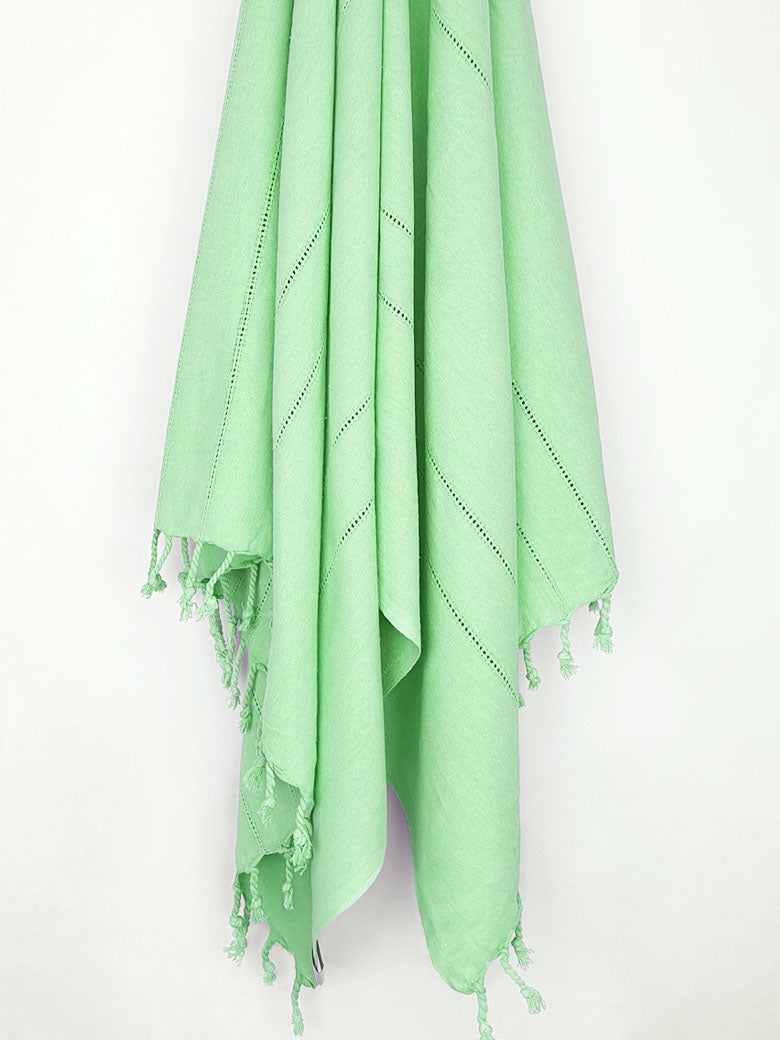 Cotton scarf in plain green colour with knotted fringe hanging.