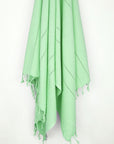 Cotton scarf in plain green colour with knotted fringe hanging.