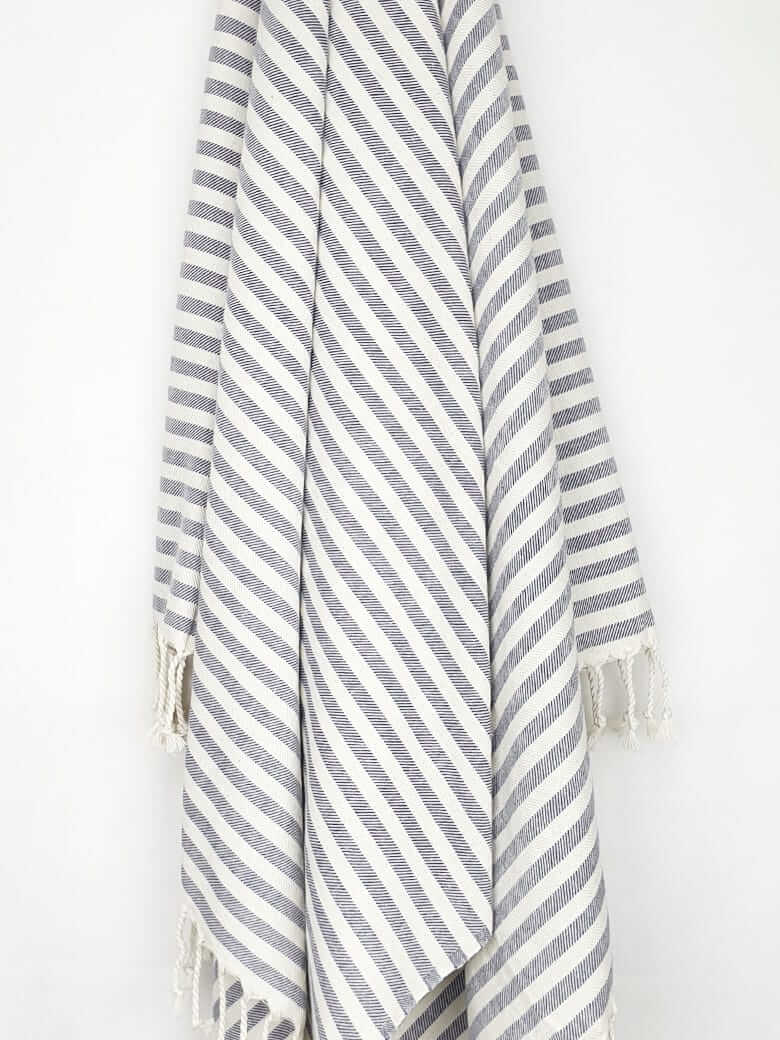 Cotton towel with navy stripes and hand-twisted &amp; knotted fringe hanging.