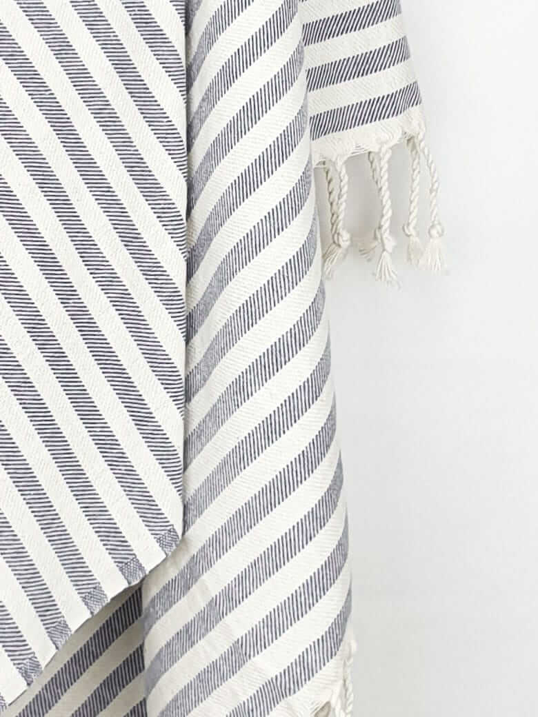 Close-up image of the cotton towel with navy stripes and hand-twisted & knotted fringe.