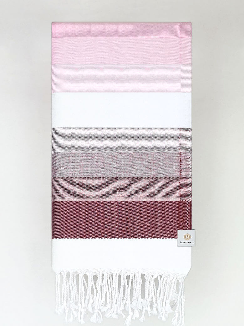 Folded a beach towel with stripe maroon tonal colours and knotted fringe.