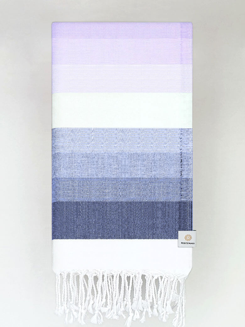 Folded a beach towel with stripe navy tonal colours and knotted fringe.