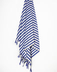 Large towel with blue thick stripes colour and knotted fringe hanging.