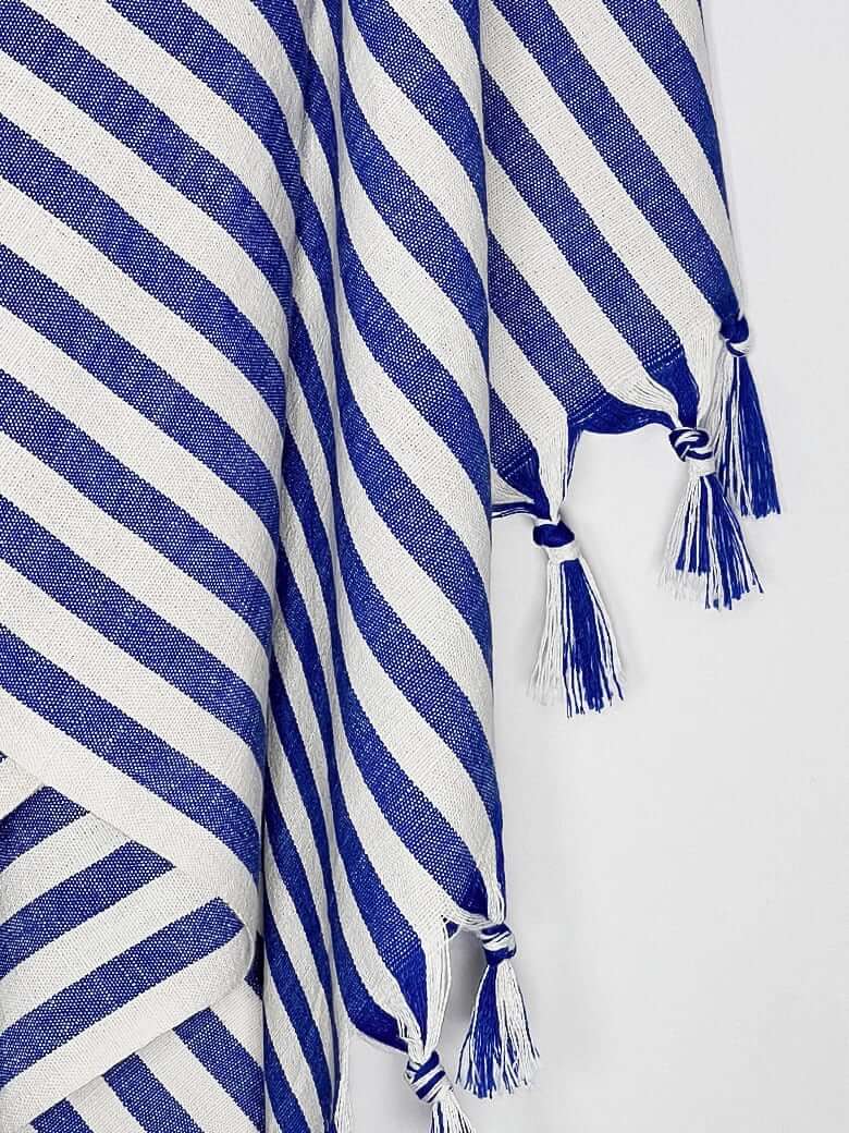 Close-up image of a large towel with blue thick stripes colour and knotted fringe.