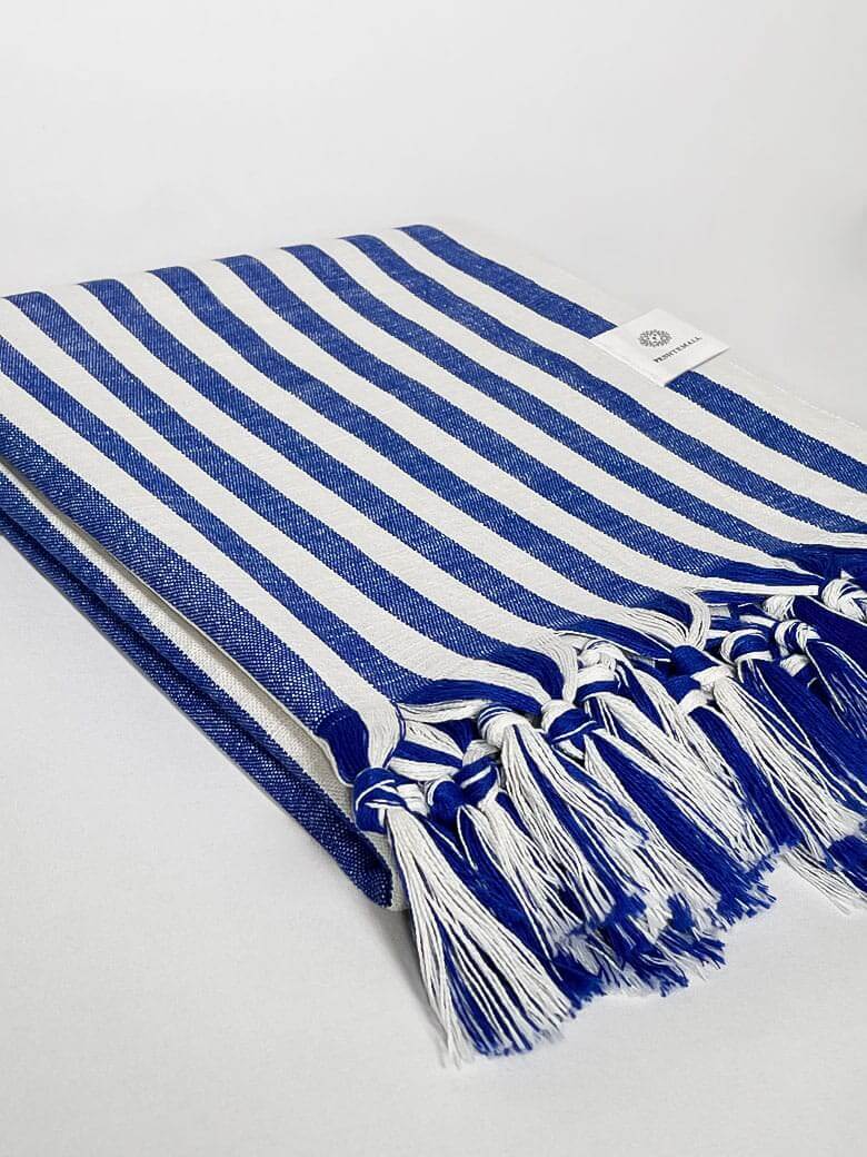 Side image of a large towel with blue thick stripes colour and knotted fringe.