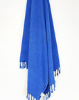 Beach towel in plain blue colour with knotted fringe hanging.