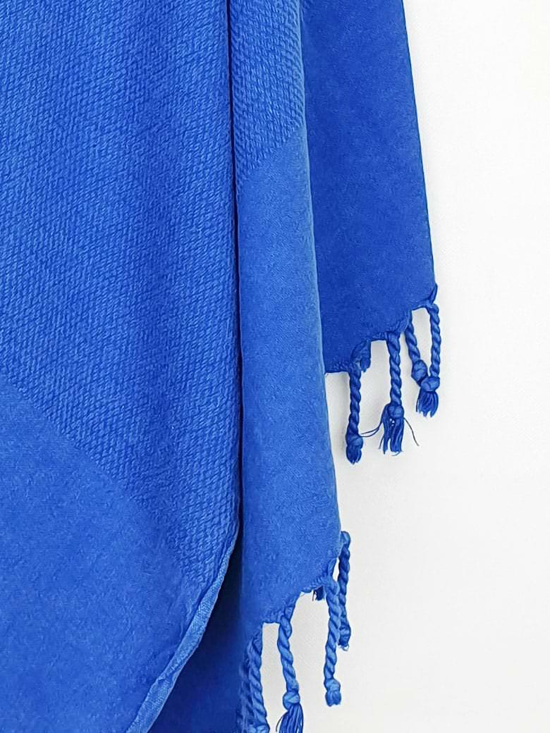 Close-up image of beach towel in plain blue colour with knotted fringe.