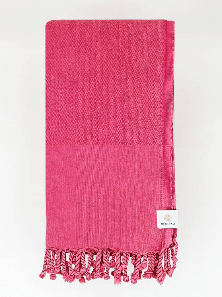 Folded beach towel in plain rose colour.