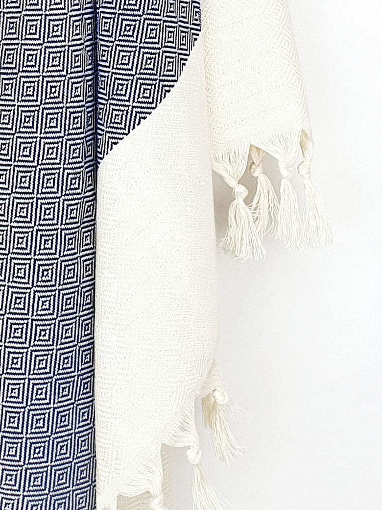 Close-up image of a diamond pattern towel in navy colour with knotted fringe.