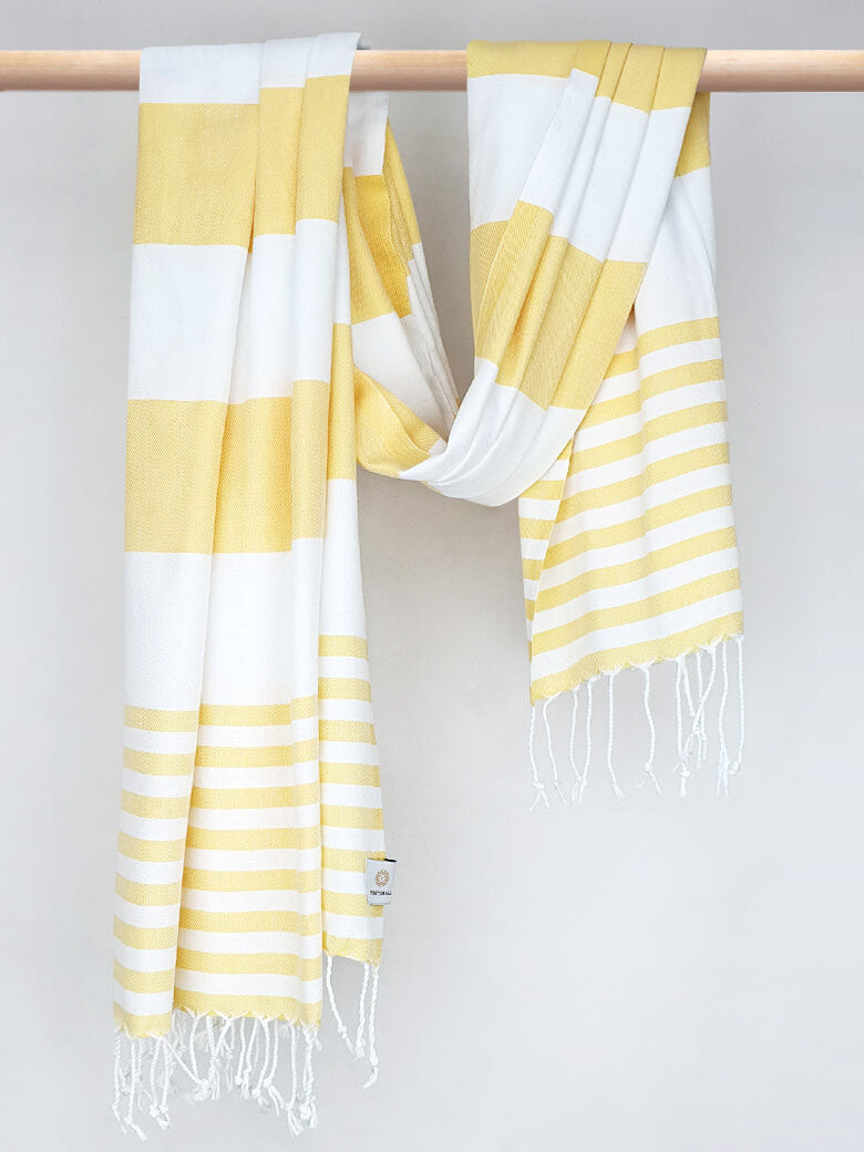 Beach towel with yellow and white colours stripes and knotted fringe with hand-twisted style on the stick.