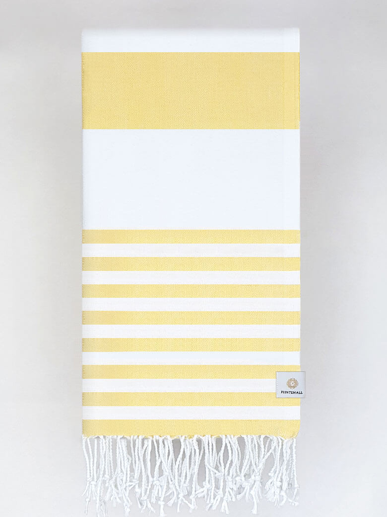Folded beach towel with yellow and white colours stripes and hand-twisted & knotted fringe.