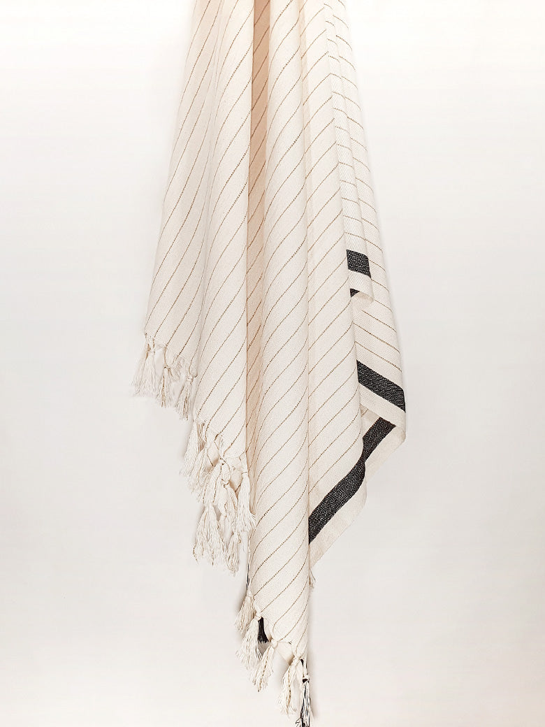 Towel with black stripes on beige colour and knotted fringe hanging.
