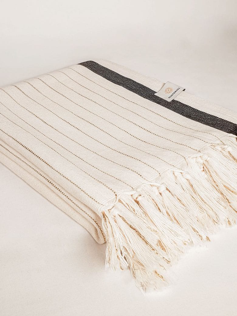 Side image of a towel with black stripes on beige colour and knotted fringe.