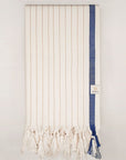Folded towel with navy stripes on beige colour and knotted fringe.