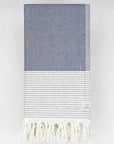Folded towel in denim colour with horizontal stripes and knotted fringe.