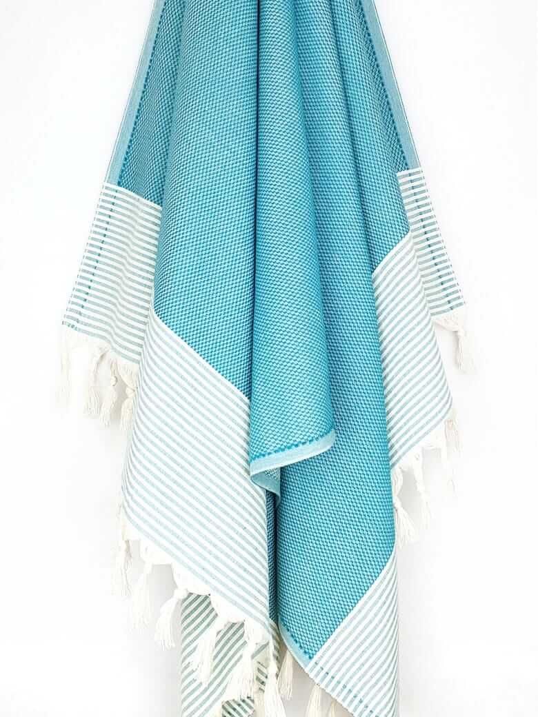 Towel in sea green colour with horizontal stripes and knotted fringe hanging.