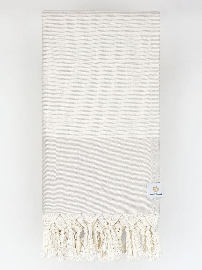 Folded a beige colour towel with white stripes and knotted fringe.