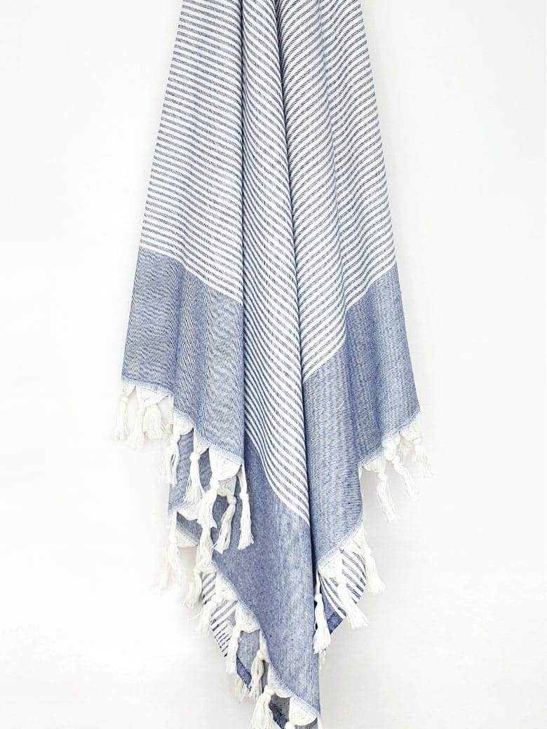 Denim colour towel with white stripes and knotted fringe hanging.	