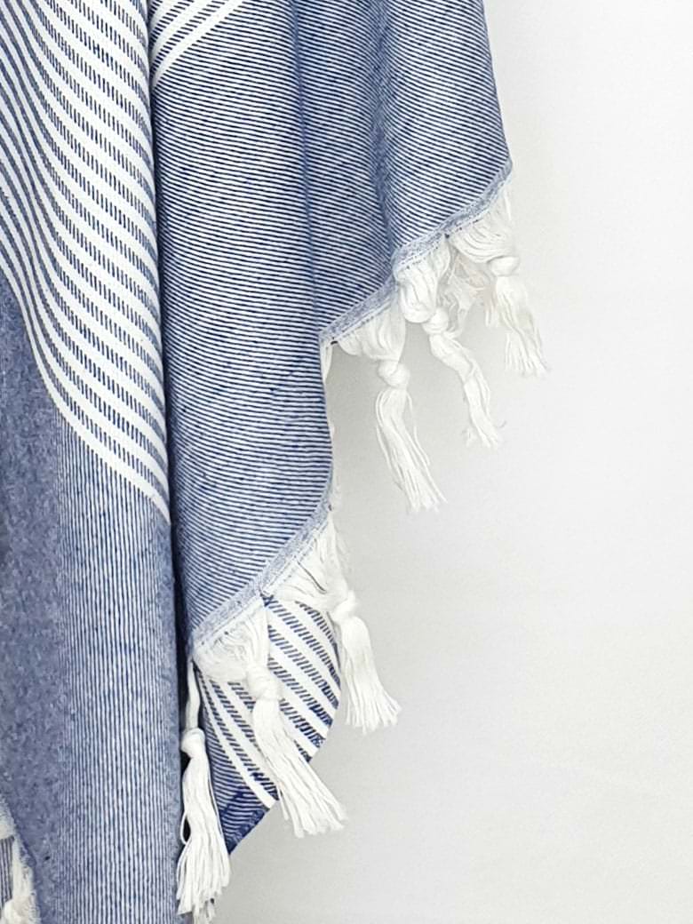 Close-up image of a denim colour towel with white stripes and knotted fringe.