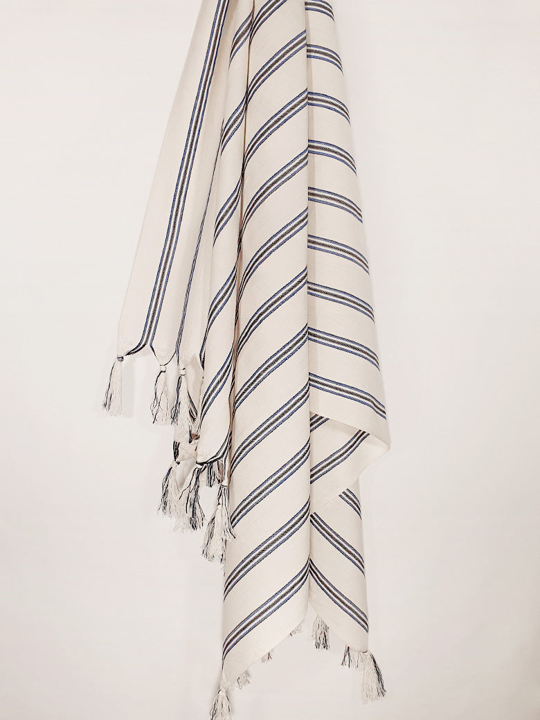 Beige towel with vertical blue &amp; black stripes colours and knotted fringe hanging.