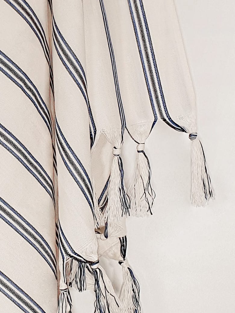 Close-up image of a beige towel with vertical blue & black stripes colours and knotted fringe.