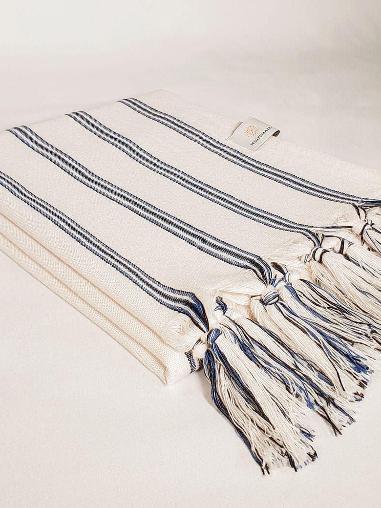 Side image of a beach towel with vertical blue &amp; black stripes colours and knotted fringe.