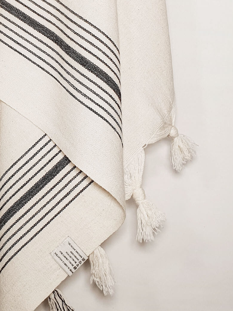 Close-up image of plain beige hammam beach towel with vertical black stripes.