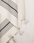 Close-up image of plain beige hammam beach towel with vertical black stripes.