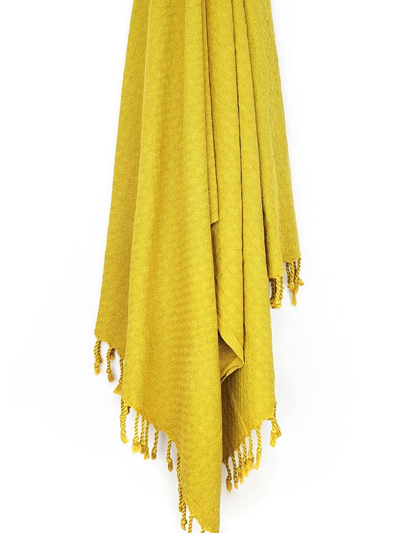 Towel in plain mustard colour with a honeycomb texture hanging.