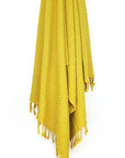 Towel in plain mustard colour with a honeycomb texture hanging.